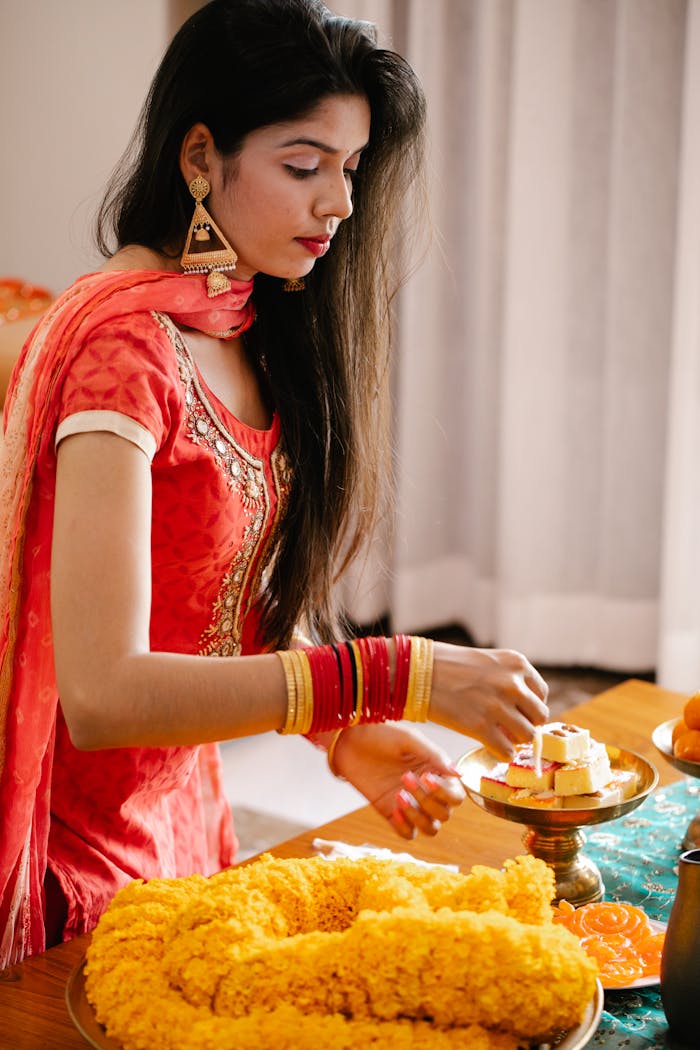 A young woman in traditional Indian clothing prepares for a festival celebration indoors.